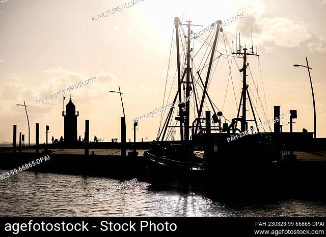 23 March 2023, Lower Saxony, Wremen: A crab cutter lies in sunny weather in the cutter harbor in front of the lighthouse Kleiner Preuße in the municipality of...