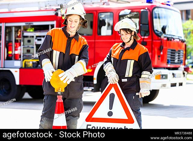 Female fire fighters in emergency operation setting up attention sign