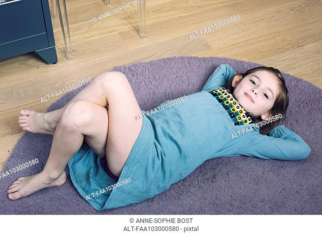 Girl lying on floor with hands behind head, smiling