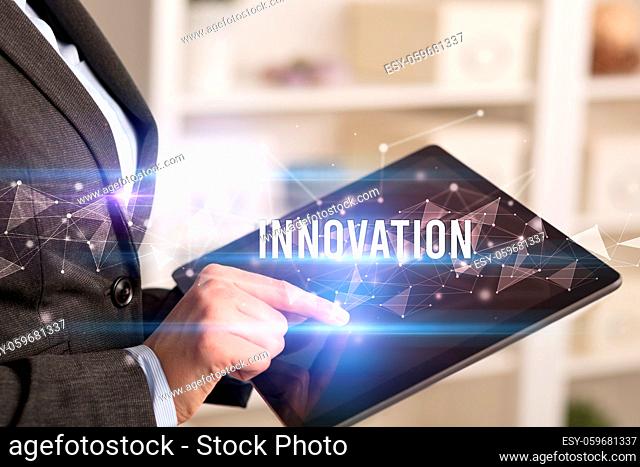 Close up hands using tablet with INNOVATION inscription, modern business technology concept