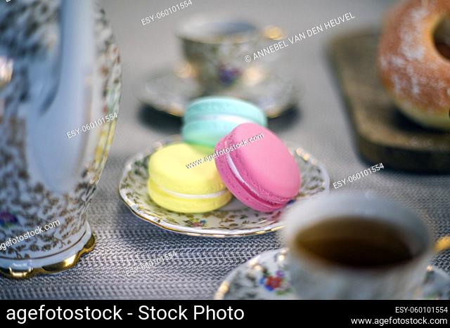 Traditional table with cup of tea and tea pot and colorful macaron lovely cozy table at home, Mother's Day tea setting with teapot, close up