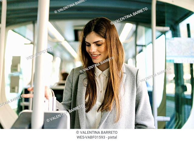 Portrait of smiling young woman validating ticket in tramway