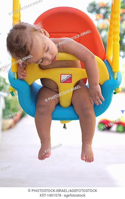 Baby boy fast asleep on a swing
