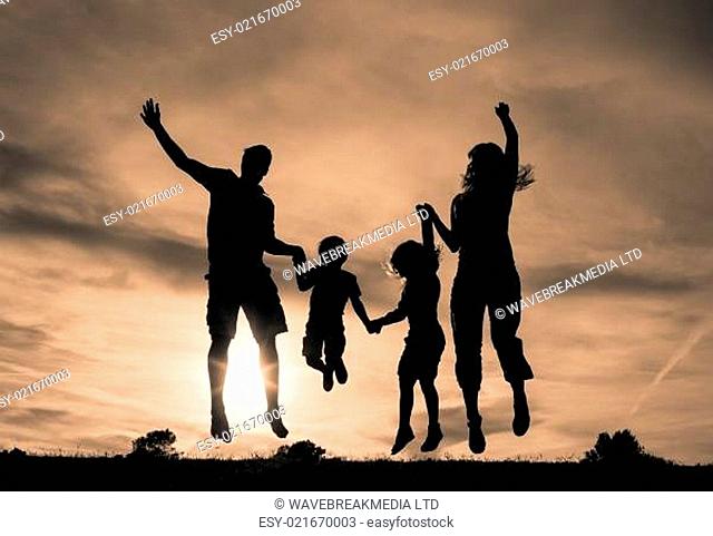 Silhouette of family jumping together at sunset in the park
