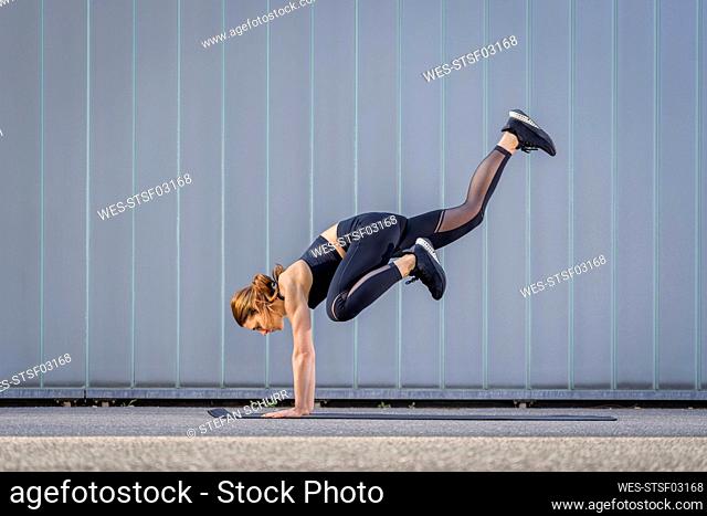 Woman balancing on hands exercising in front of wall