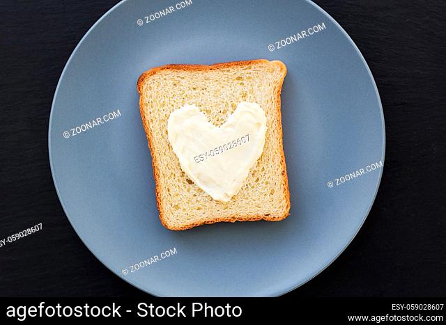 sandwich for breakfast in the form of heart with cheese on a blue plate and black background