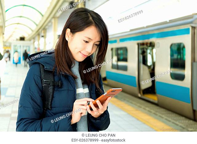 Woman read on cellphone in train platform