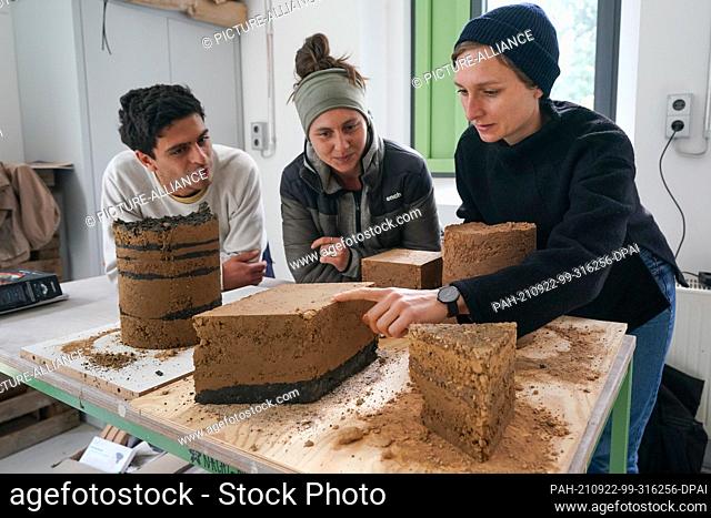 22 September 2021, Saxony-Anhalt, Halle: Students (l-r) Taufiq El-Mokdad and Johanna Schmidtke talk to research assistant Sarah Kaiser about rammed earth study...