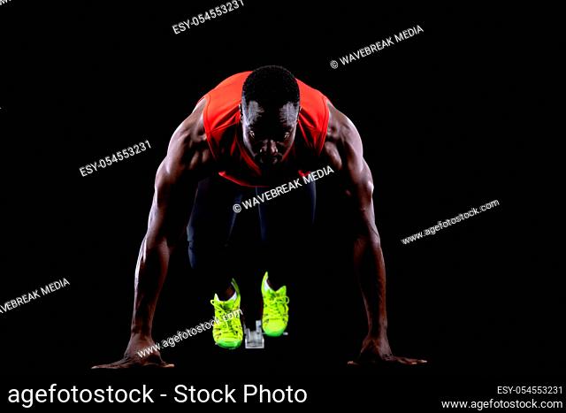 Front view close up of a fit handsome young muscular African American male runner on starting blocks, ready to race