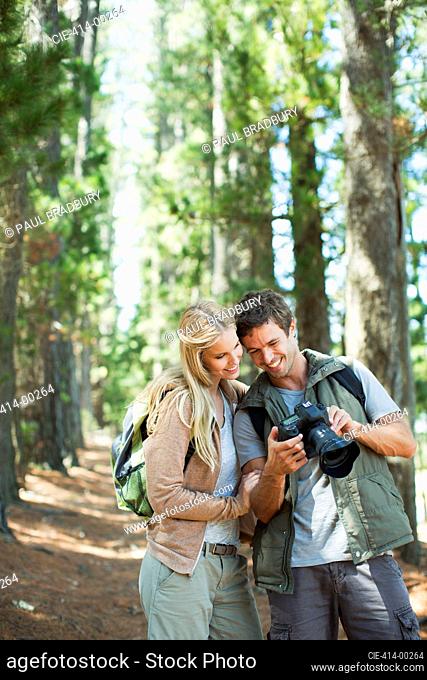 Smiling couple looking at digital camera in woods