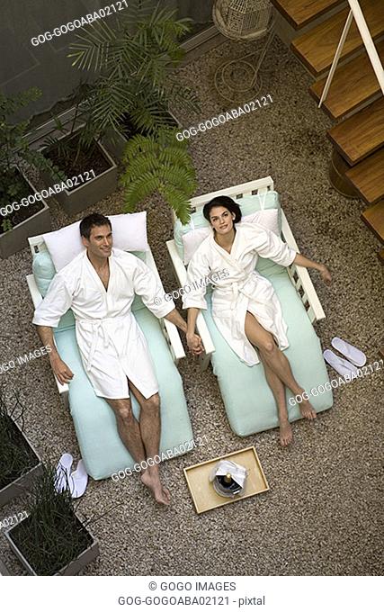Couple relaxing in bathrobes in lawn chairs
