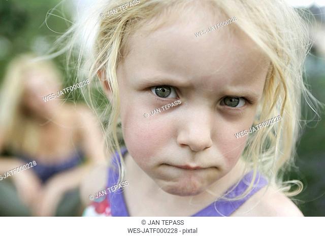 Germany, North Rhine Westphalia, Cologne, Portrait of girl biting lips while her mother in backgroud, close up
