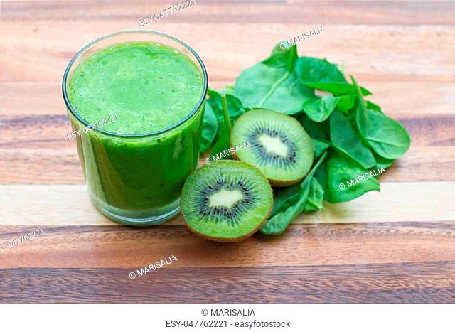 green smoothie with spinach and kiwi on wood background