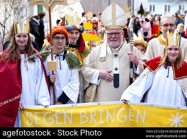 28 December 2022, Bavaria, Bad Tölz: Cardinal Reinhard Marx (4th from left), Archbishop of Munich and Freising, poses for a photo with the carol singers after...