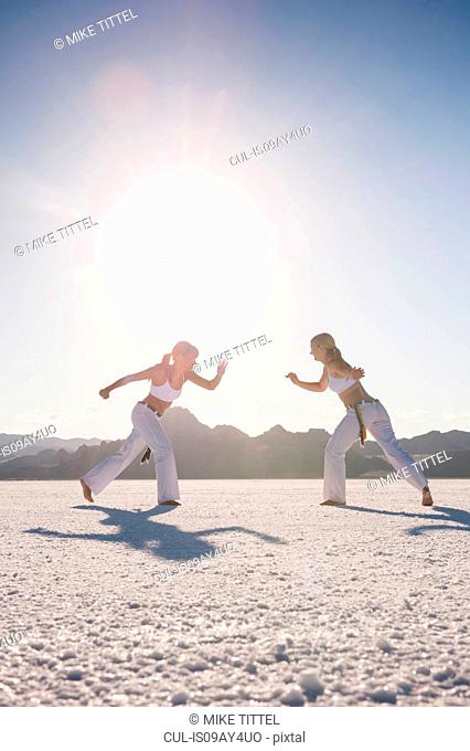 Surface level view of two women performing capoeira on Bonneville Salt Flats, Utah, USA