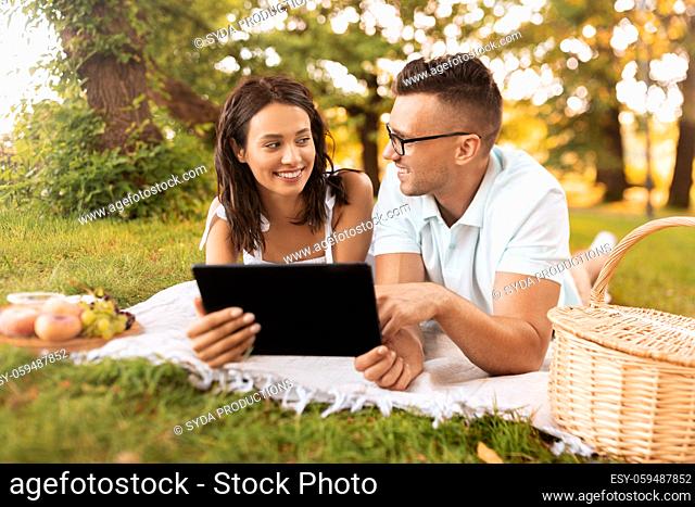 happy couple with tablet pc at picnic in park