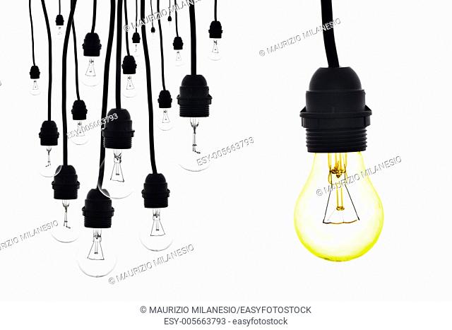 A yellow light bulb next to a number of light bulbs hanging on white