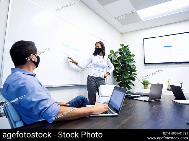 Businesswoman in face mask giving presentation in office