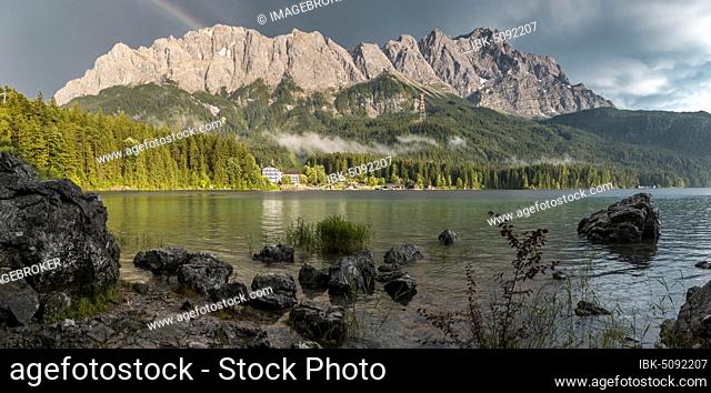 Rocks on the shore, Eibsee lake in front of Zugspitze massif with Zugspitze with rainbow, Wetterstein range, near Grainau, Upper Bavaria, Bavaria, Germany
