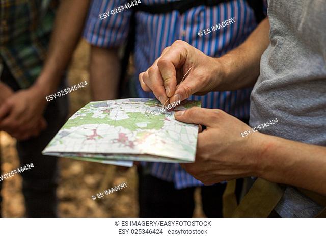 A group of hikers uses map and compass to navigate through the forest