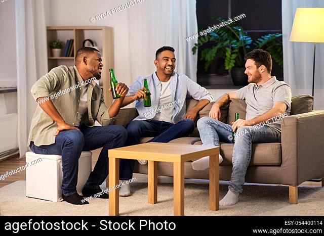 happy male friends drinking beer at home at night