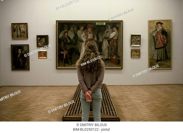 Caucasian teenage girl admiring paintings in museum
