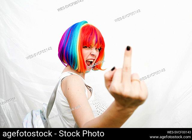 Woman doing obscene gesture in front of plastic backdrop