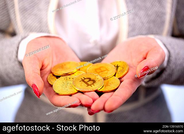 Virtual cryptocurrency money Bitcoin golden coins in the hands of a woman with red nail polish. The future of money