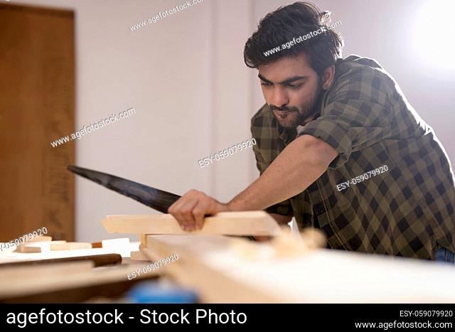 A CARPENTER CAREFULLY USING TOOLS TO CUT WOOD