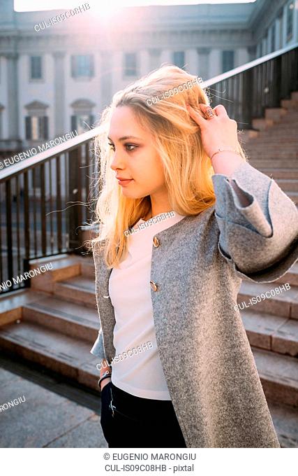 Young woman with long blond hair on stairway, Milan, Italy