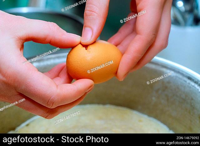 Cook breaking egg into the bowl in a bakery