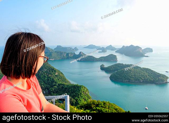 Woman tourist on the balcony is peak view point of Ko Wua Ta Lap island looking beautiful nature landscape during sunrise over the sea in Mu Ko Ang Thong...