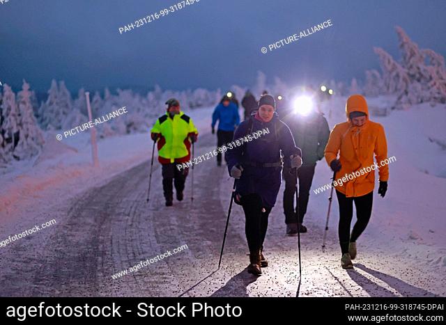 16 December 2023, Saxony-Anhalt, Schierke: Hikers walk over the Brocken in the early hours of the morning at the Brocken breakfast with geocaching