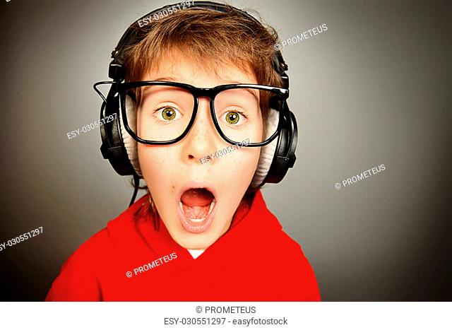 Funny boy gamer in headphones and glasses looking at camera and shouting. Studio shot