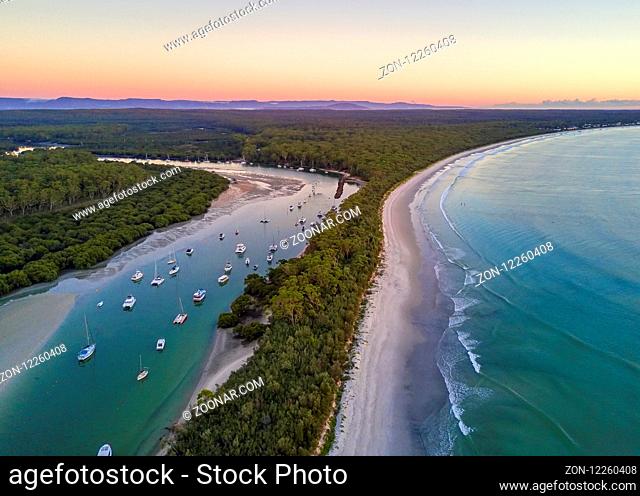 Scenic coastal landscape beautiful beach and inlet with moored yachts and boats. Morning sky at dawn with soft light. Australia