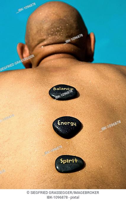 Elderly senior citizen at wellness spa with stones on his back