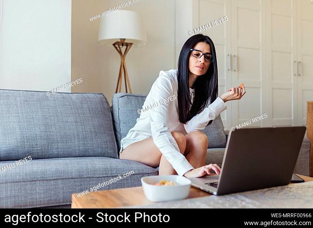 Woman using laptop while sitting on sofa in living room