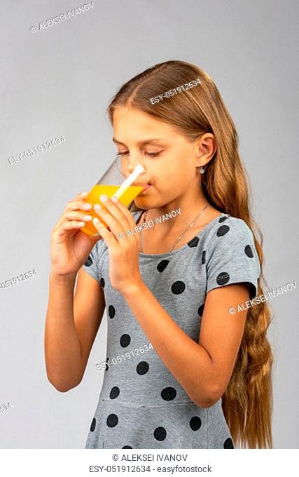 A ten-year-old girl drinks juice, half-sided view