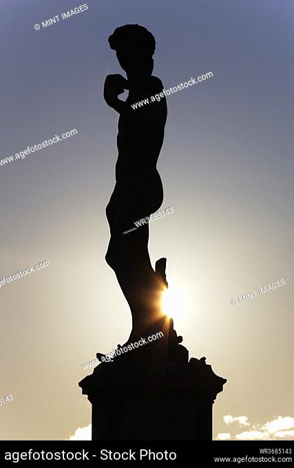 Silhouette of classical statue with setting sun behind