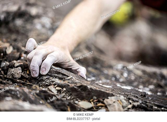 Hand of Caucasian man rock climbing