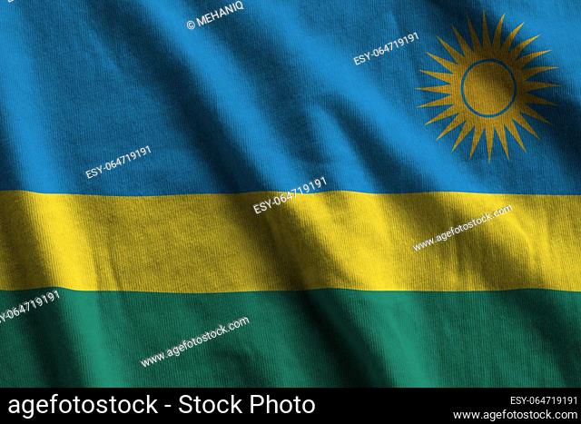 Rwanda flag with big folds waving close up under the studio light indoors. The official symbols and colors in fabric banner