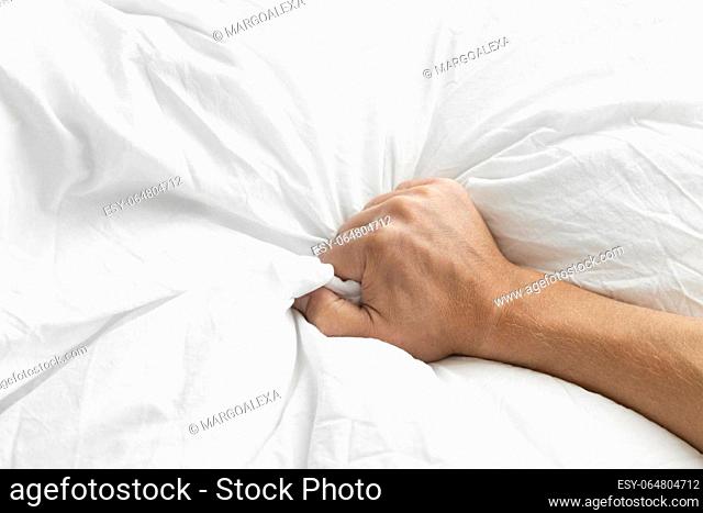 Man's hand squeezing a blanket, vintage white, soft focus. High quality photo