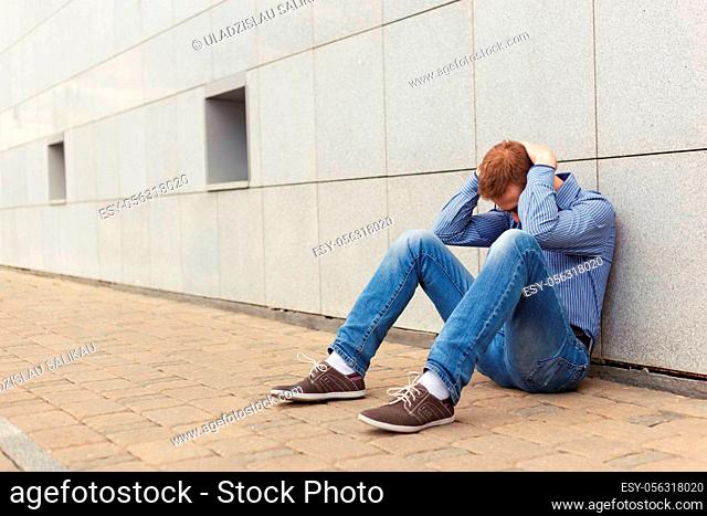 Upset man sits holding his hands behind his head