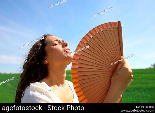 Stressed woman fanning suffering heat stroke in a field in summer vacation