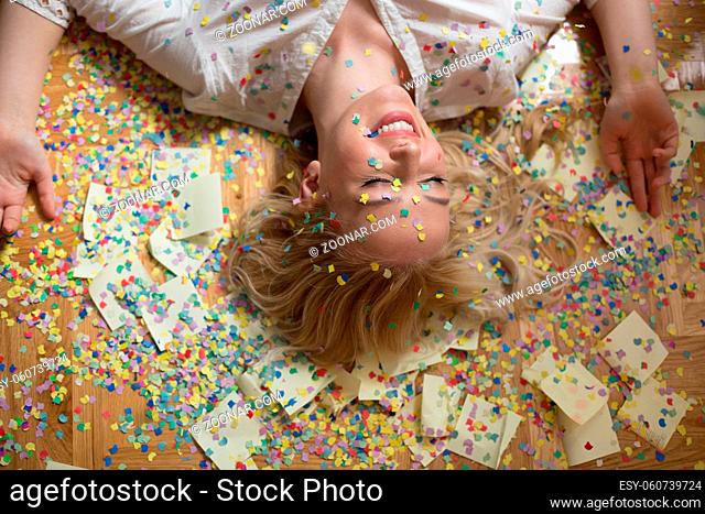 Cheerful young woman is stretching out her hands while confetti falling on her