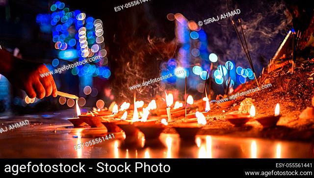 Hands light a candle from a clay diya during Diwali festival closeup