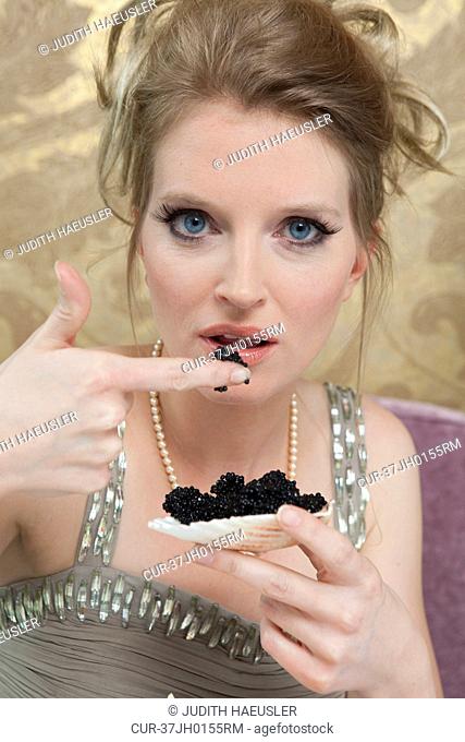 Woman in evening gown eating caviar