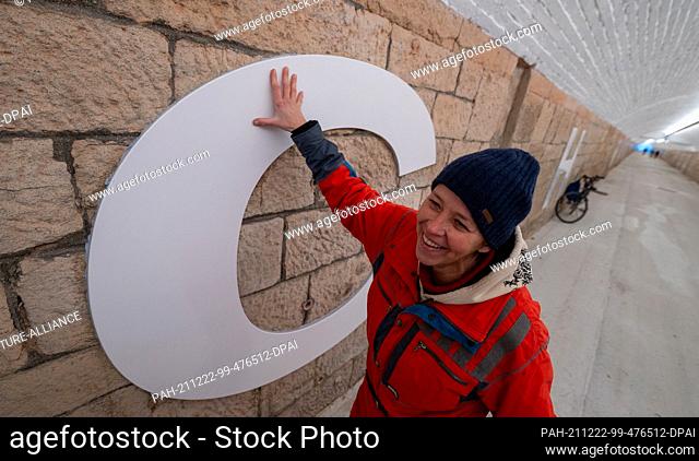 22 December 2021, Saxony, Chemnitz: Artist Anke Neumann stands by the letter ""C"" in the newly designed pedestrian tunnel at Chemnitz central station