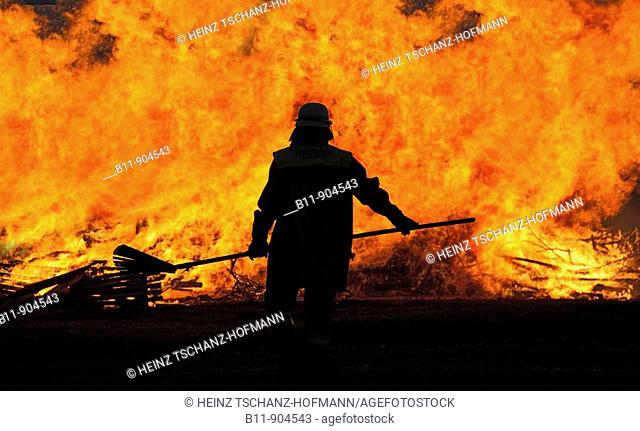 Feuerwehrmann steht vor Flammenwand / Fireman in front of fire