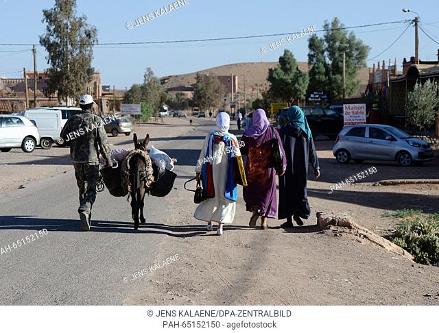 A man walks down a street with a donkey and three women who are wearing traditional clothes near Ait Benhaddou, Morocco, 08 November 2015